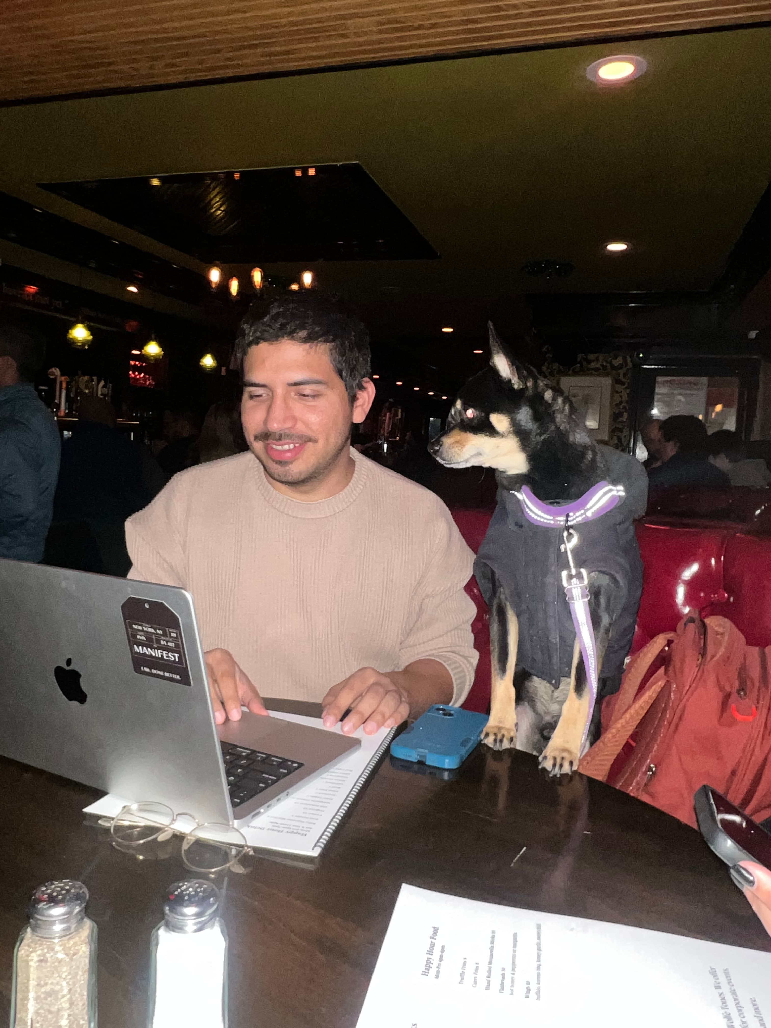 Caryl Espinoza Jaen, working at a bar table with his dog Prince